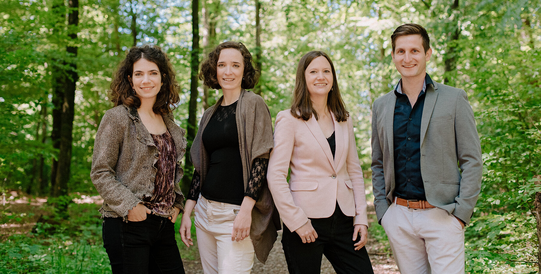 The Belenus Quartett in a summer forest, four musicians among green trees